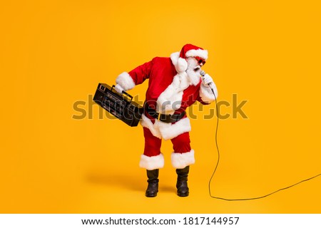 Full length photo of crazy grey white hair santa claus with beard hold boom box sing pop star song on christmas x-mas disco wear headwear cap isolated bright shine color background