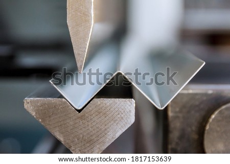 Bending of galvanized sheet metal on a hydraulic bending machine at the factory. Royalty-Free Stock Photo #1817153639