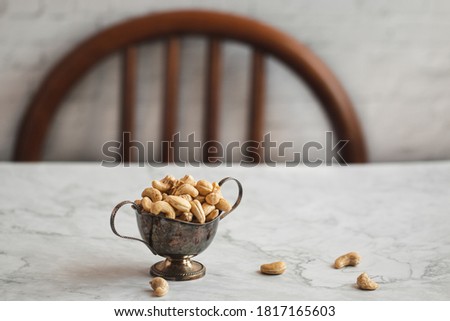 Raw cashews in wooden bowl on a white marble background, highkey photography