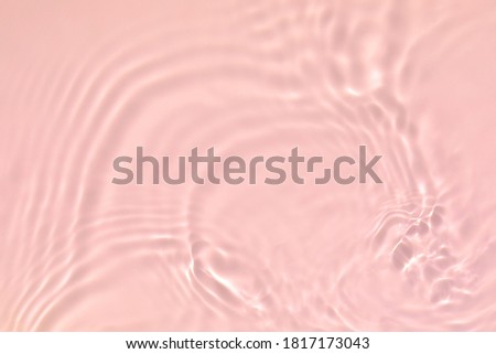 de-focused. Closeup of pink transparent clear calm water surface texture with splashes and bubbles. Trendy abstract summer nature background. Coral colored waves in sunlight.