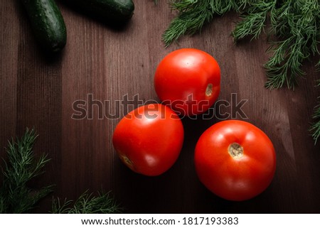 tomatoes and cucumbers are decorated with greenery on a wooden table