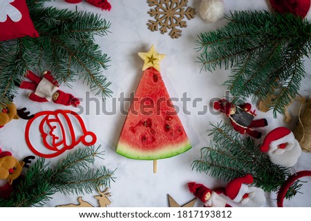 New Year's food. Christmas tree made of watermelon top view. Christmas decor on the table. Festive still life. Spruce branches and decorations. Creative ideas.