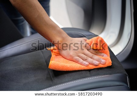 Man's hand cleaning car interior in luxury car with microfiber cloth. Hand wipe down suede leather seat of sports sedan.  Interior car detail & leather seat repair background. Car wash & clean concept Royalty-Free Stock Photo #1817203490