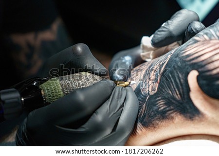 Tattooer doing black tattoo of snake for woman