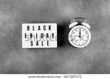 Black friday sale word on lightbox and alarm on gray background table. Flat lay, top view