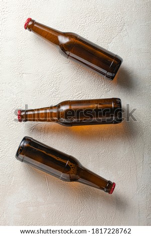 Three bottles of beer on the background of light concrete.