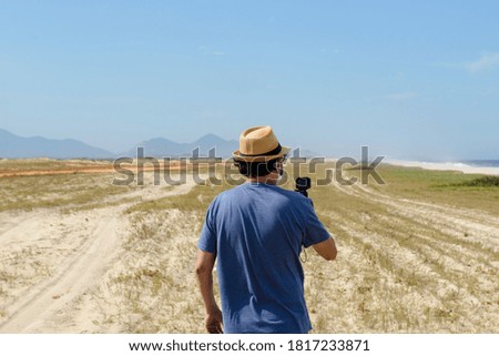 The new normal - middle-aged man takes a picture of the beach in a place without agglomeration, wearing a protective mask tells the covid-19