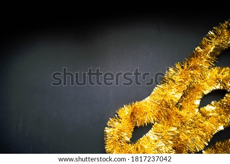 Christmas golden tinsel on black background. Happy New Year banner, Merry Christmas. Xmas posters, greeting cards, headers, website, sale banner. Space for text. Top view.
