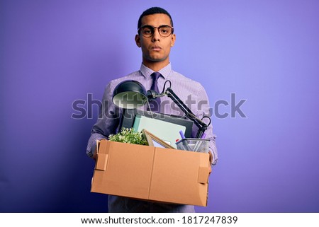 Handsome african american man fired holding box with work objects over purple background with a confident expression on smart face thinking serious