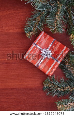 The frame is made of coniferous trees with green branches on a wooden table in the center is a gift box. Concept of the new year, celebrating the family holiday of Christmas. Vertical photo