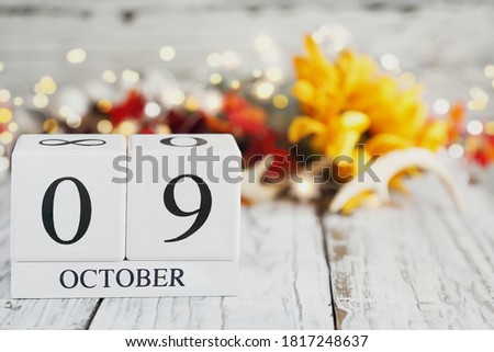 Canadian Thanksgiving Day. White wood calendar blocks with the date October 9th and autumn decorations over a wooden table. Selective focus with blurred background. 