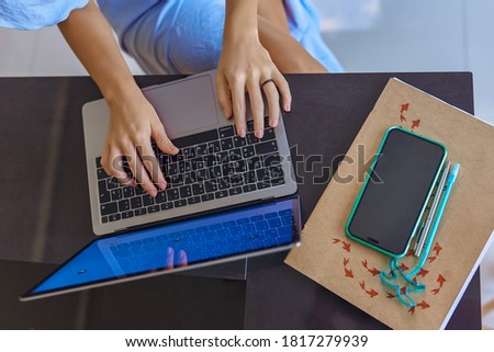 Photo of women's hands with laptop, phone, notebook and handle on granite table