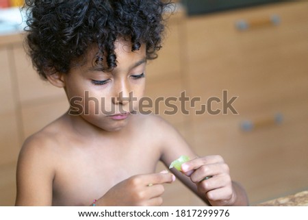 Curly haired hispanic boy eating grape Royalty-Free Stock Photo #1817299976