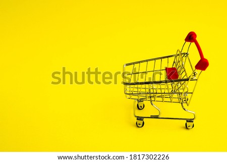 shopping cart on a yellow background. Theme of purchases and sales.