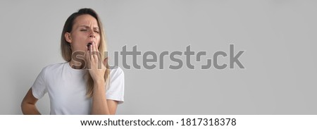 Yawning tired bored woman. Beautiful caucasian model isolated on grey studio background, headshot. copy space, banner