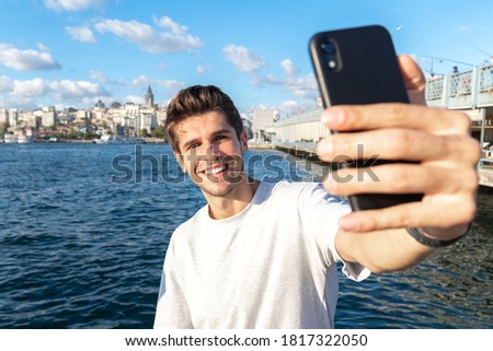 Young handsome man is taking a selfie with his phone near Galata bridge tourist spot 