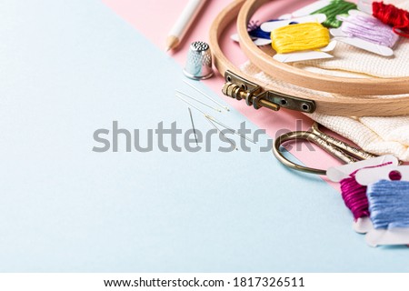 Embroidery set fot cross stitching. White fabric, embroidery hoop, colorful threads, scissors and needls. On blue background. Hobbies concept with copy space. Royalty-Free Stock Photo #1817326511