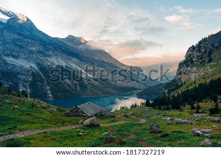 Idyllic panorama view of the lake Oeschinensee. Picture or postcard view of Oeschinen Lake by Kandersteg, Switzerland. Turquoise lake with steep mountains and rocks in background. Swiss Alps.
