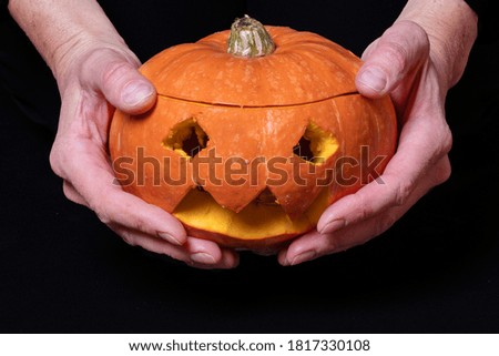 Hands hold Jack Lantern, Smiling Halloween pumpkin with eyes carved from an orange pumpkin, preparing for the holiday
