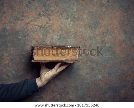 Male hand with antique book on grunge background