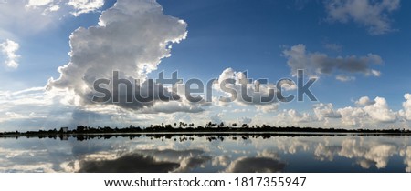 Beautiful clouds in blue sky with reflection in calm water in the morning lake. Nature wallpaper