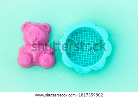 Plastic bear and sieve on turquiose background