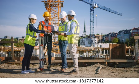 Diverse Team of Specialists Use Tablet Computer on Construction Site. Real Estate Building Project with Civil Engineer, Architect, Business Investor and Surveyor with Theodolite Discussing Plans. Royalty-Free Stock Photo #1817377142