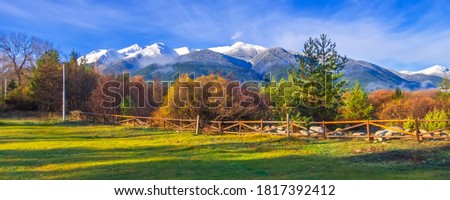 Bansko, Bulgaria autumn banner landscape with wooden fence, colorful trees, Pirin mountains snow peaks Royalty-Free Stock Photo #1817392412