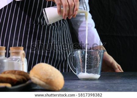 Chef is Pouring Milk into The Measuring Cup Royalty-Free Stock Photo #1817398382