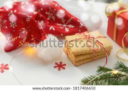 Festive Christmas flat lay with Santa hat, cookies, gift and bokeh lights.Christmas card