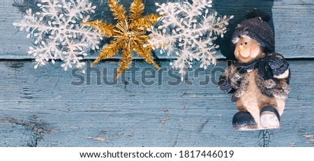 Beautiful blue Christmas banner with a snowman, white snowflakes and a Golden shiny star. Wooden Christmas background, top view. Place for text on a new year's background.