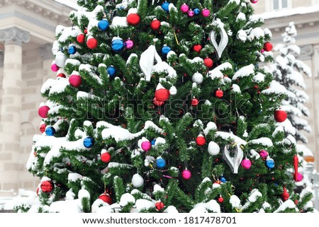 part of a spruce on the street in the snow, decorated with Christmas toys, against the background of the building, close-up with a blurred background. new year mood, Christmas, selective sharpness