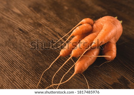 Ugly carrot on a wooden background. Funny, unnormal vegetable or food waste concept. Horizontal orientation Royalty-Free Stock Photo #1817485976