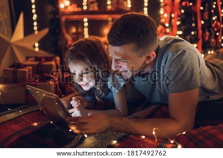 Cute girl using tablet with dad at home.