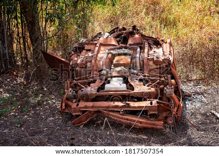 Rusting hulk wreck of a car left abandoned in the bush with many of its parts missing Royalty-Free Stock Photo #1817507354