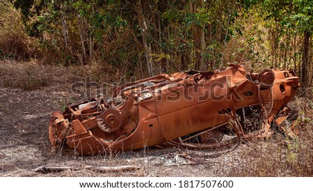 Rusting hulk wreck of a car left abandoned in the bush with many of its parts missing Royalty-Free Stock Photo #1817507600