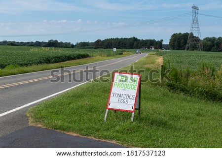 A handmade sign advertising farm products on the side of a country road.