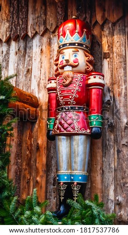 
New Year's toy nutcracker on a wooden background with fir branches, side view close-up.
