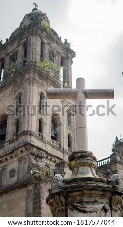 Concrete Cross and Skulls with One Bell Tower of the Cathedral of Mexico City in the Background