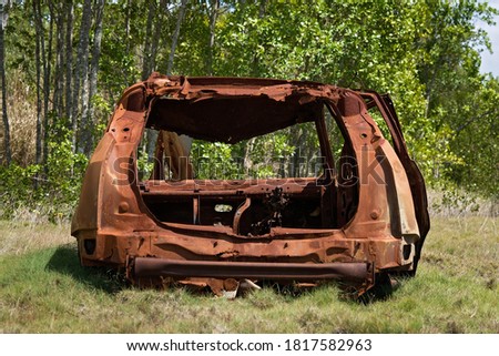 Rusting hulk wreck of a car left abandoned in the bush with many of its parts missing Royalty-Free Stock Photo #1817582963