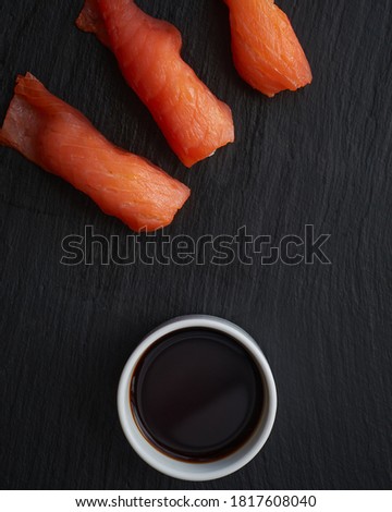 white glass with soy sauce and salmon sushi on a dark background