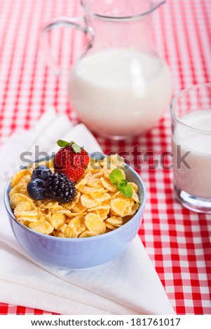 Close-up of homemade cornflakes with strawberry, blueberries,  blackberry and milk, vertical stock photo
