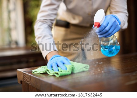 Close-up of waitress cleaning tables with disinfectant due to coronavirus epidemic.  Royalty-Free Stock Photo #1817632445