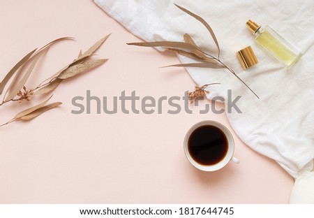 Eucalyptus leaves and a cup of black coffee with a bottle of essence on a light background with empty space