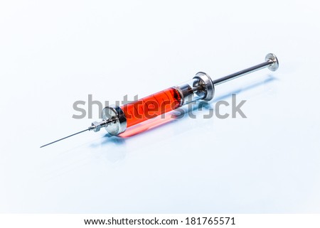 Glass syringe with metal needle with red liquid