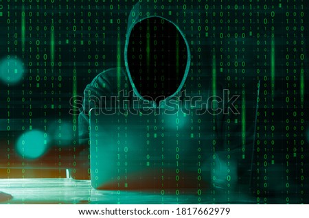 Hacker and malware concept. Dangerous Hooded hacker man using laptop with binary code digital interface.