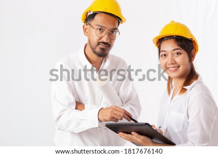 Pretty Architect and Young Engineer in construction helmets talking and discussing, Using Digital Tablet Computer, Working together with isolated on white background.