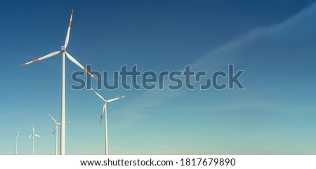 Banner with pair of big wind turbines to generate electrical power, green ecofriendly energy at blue sky with sunset warm colors with copy space for text
