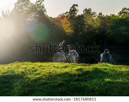 Beautiful autumn view with a cyclist resting on a hill against the background of sunlight.