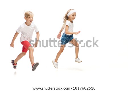 Happy kids, little caucasian boy and girl jumping and running isolated on white background. Copyspace for ad. Childhood, education, happiness concept.